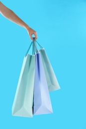 Photo of Woman with paper shopping bags on light blue background, closeup