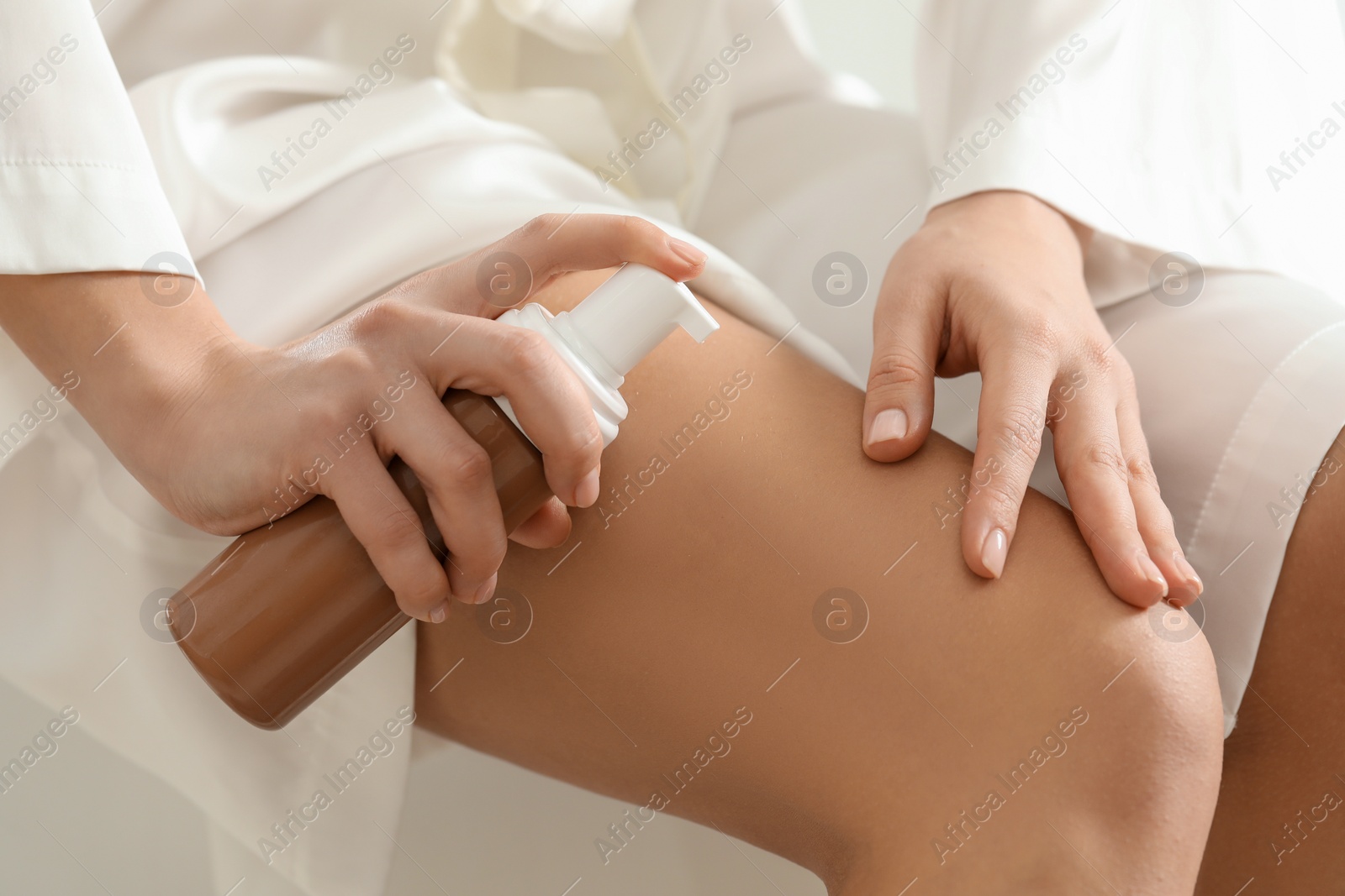 Photo of Woman applying self-tanning product onto leg, closeup