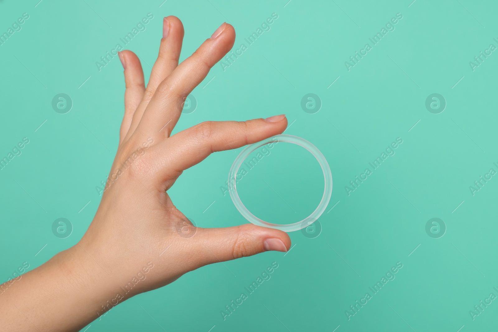 Photo of Woman holding diaphragm vaginal contraceptive ring on turquoise background, closeup. Space for text