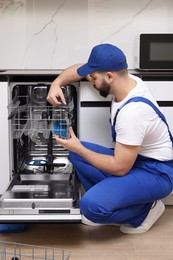 Serviceman repairing dishwasher cutlery rack in kitchen