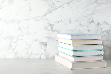 Photo of Stack of hardcover books on table against marble background, space for text