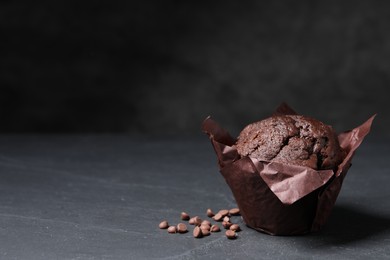 Photo of Tasty chocolate muffin on black textured table. Space for text