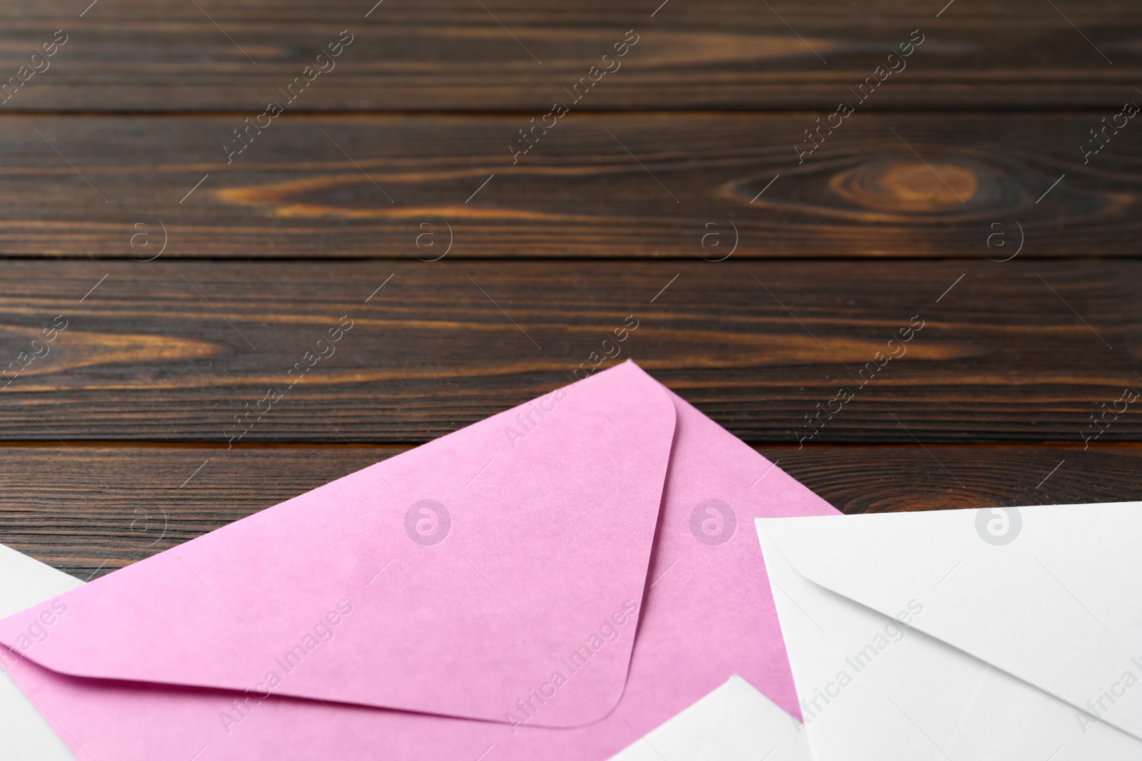 Photo of Colorful paper envelopes on wooden background, closeup. Space for text