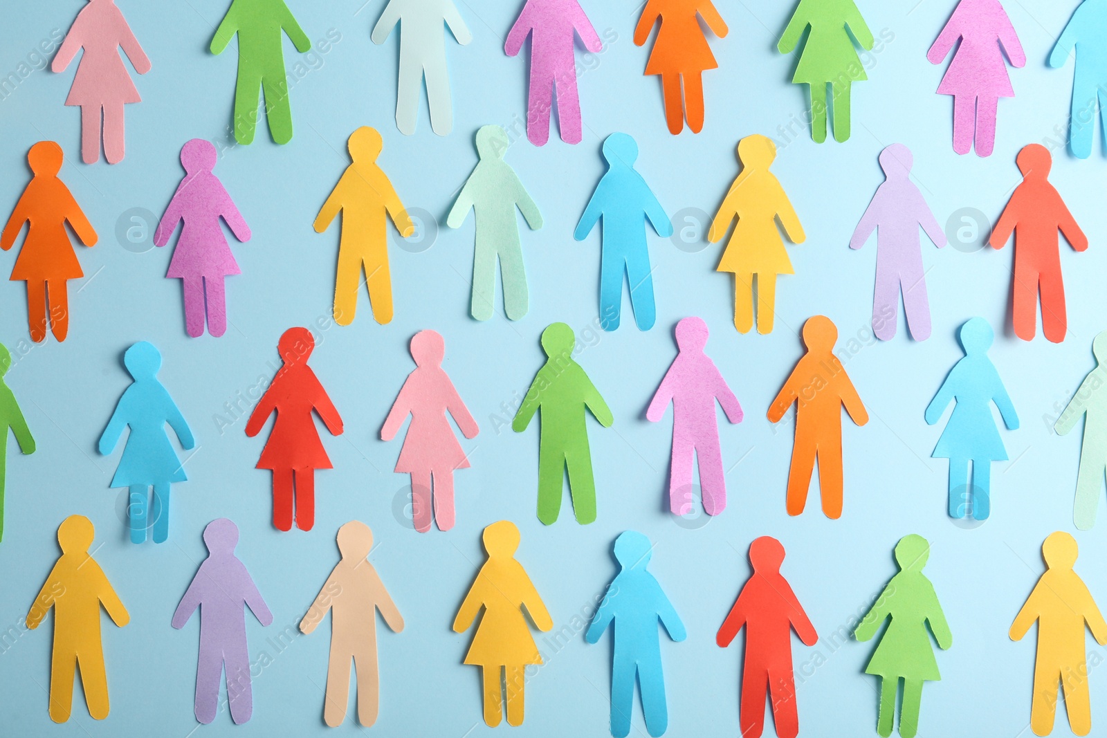 Photo of Many different paper human figures on light blue background, flat lay. Diversity and inclusion concept