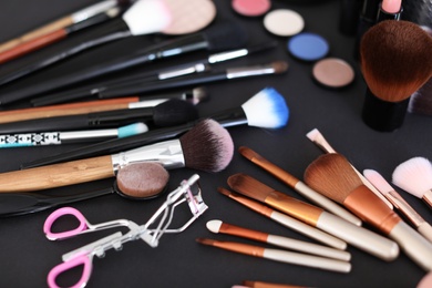 Photo of Different makeup brushes and cosmetic products on black background