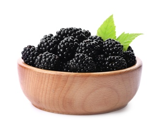 Wooden bowl of tasty ripe blackberries with leaves on white background