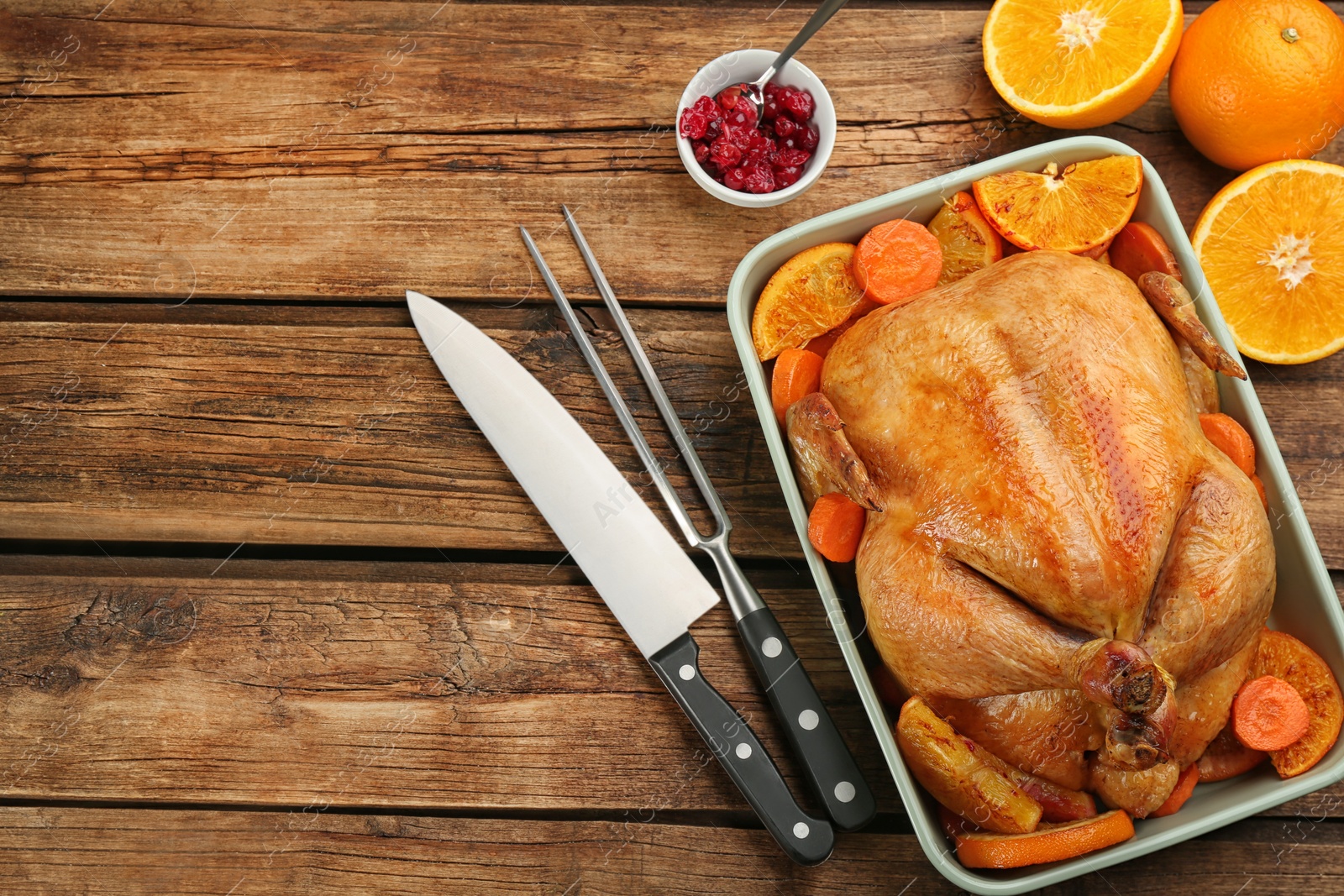 Photo of Roasted chicken with oranges and carrot on wooden table, flat lay