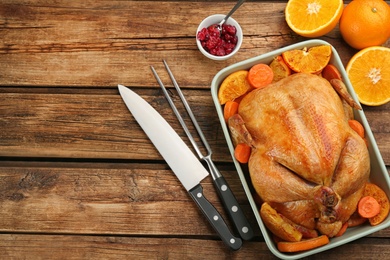 Roasted chicken with oranges and carrot on wooden table, flat lay