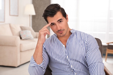 Portrait on handsome young man sitting in chair indoors