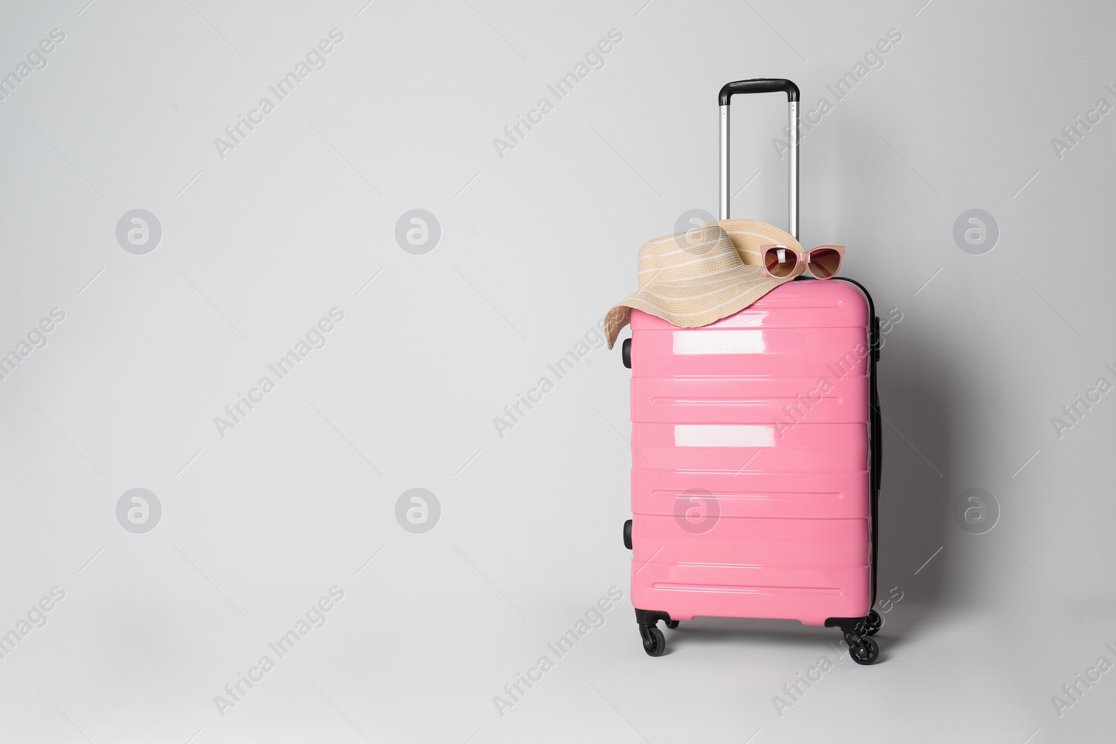 Photo of Travel suitcase with hat and sunglasses on light grey background, space for text. Summer vacation