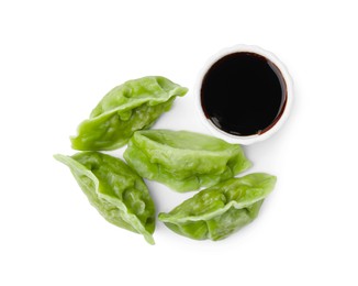 Delicious green dumplings (gyozas) and soy sauce isolated on white, top view