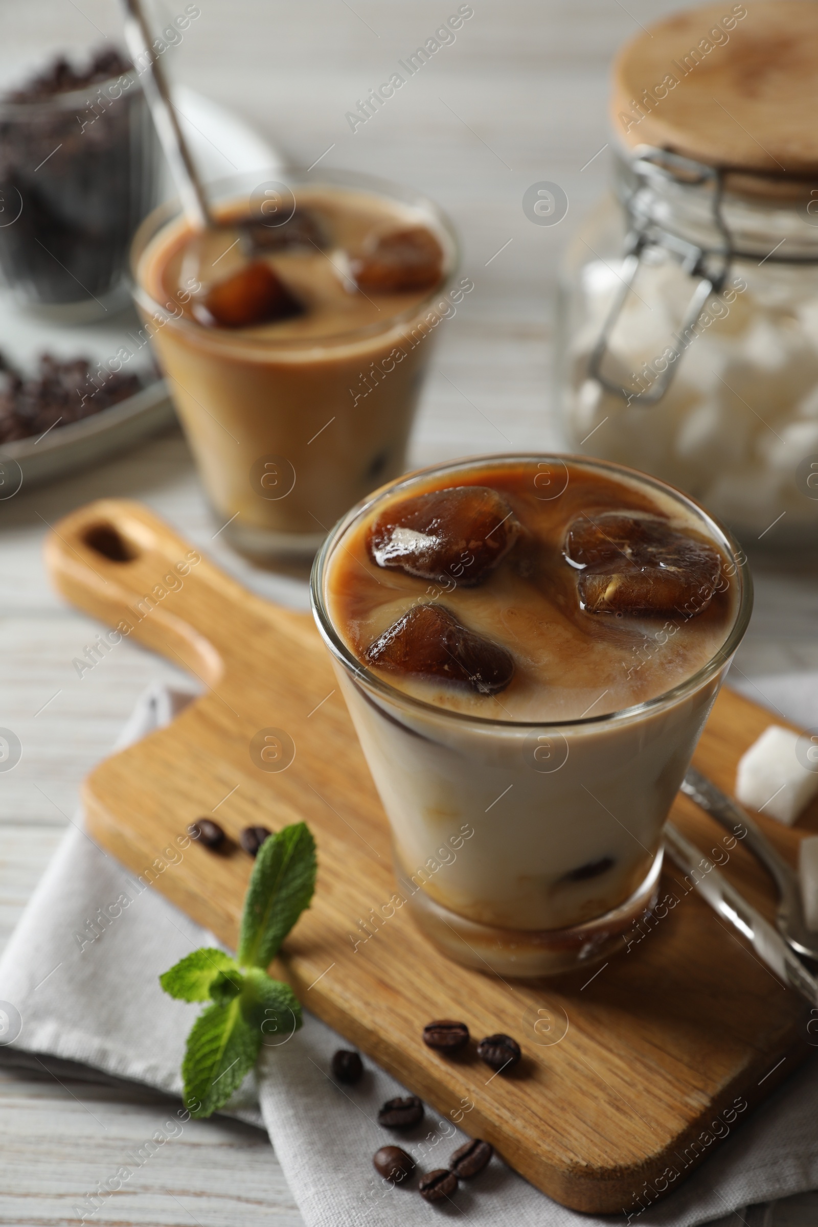 Photo of Delicious iced coffee with milk, beans and mint on white table