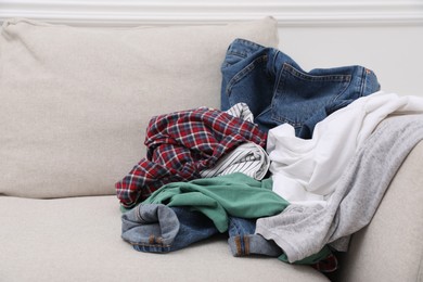 Photo of Pile of dirty clothes on sofa in living room