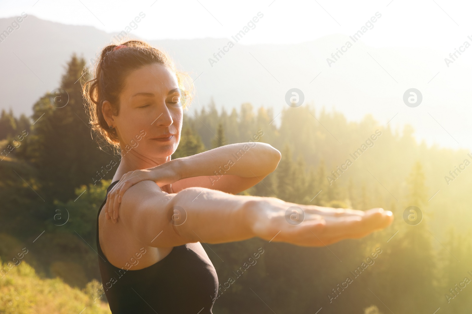 Photo of Woman practicing yoga in mountains at sunrise