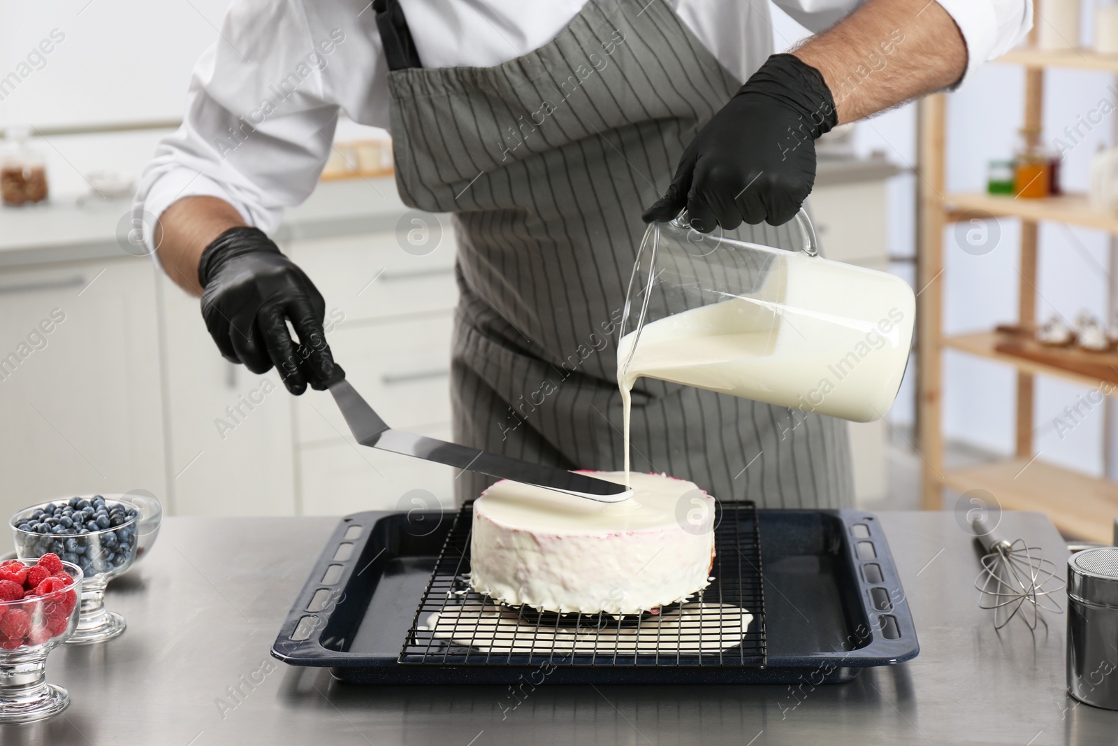 Photo of Male pastry chef preparing cake at table in kitchen, closeup