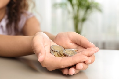 Photo of Young woman with handful of coins at table, closeup
