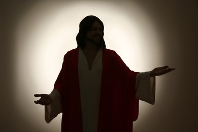 Photo of Silhouette of Jesus Christ with outstretched arms on color background
