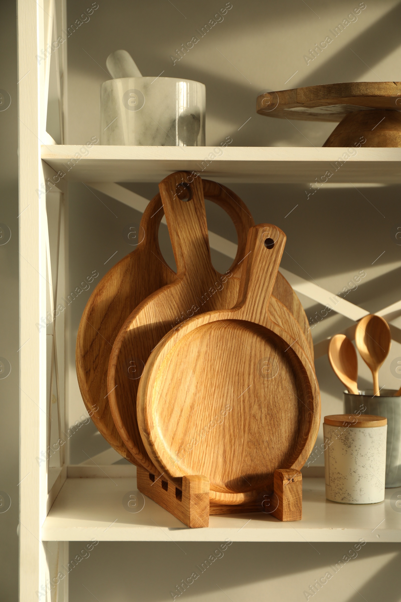 Photo of Wooden cutting boards and kitchen utensils on shelving unit