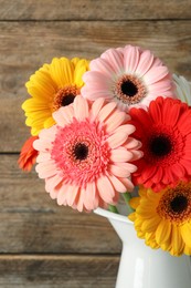 Photo of Bouquet of beautiful colorful gerbera flowers in vase on wooden background