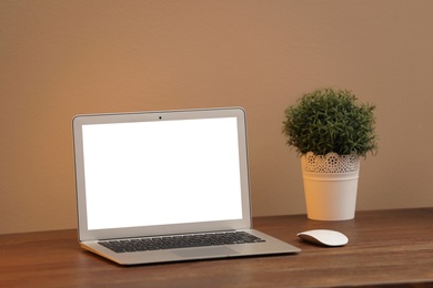 Photo of Laptop with blank screen on table indoors. Space for text