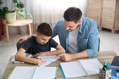 Photo of Dad helping his son with homework in room