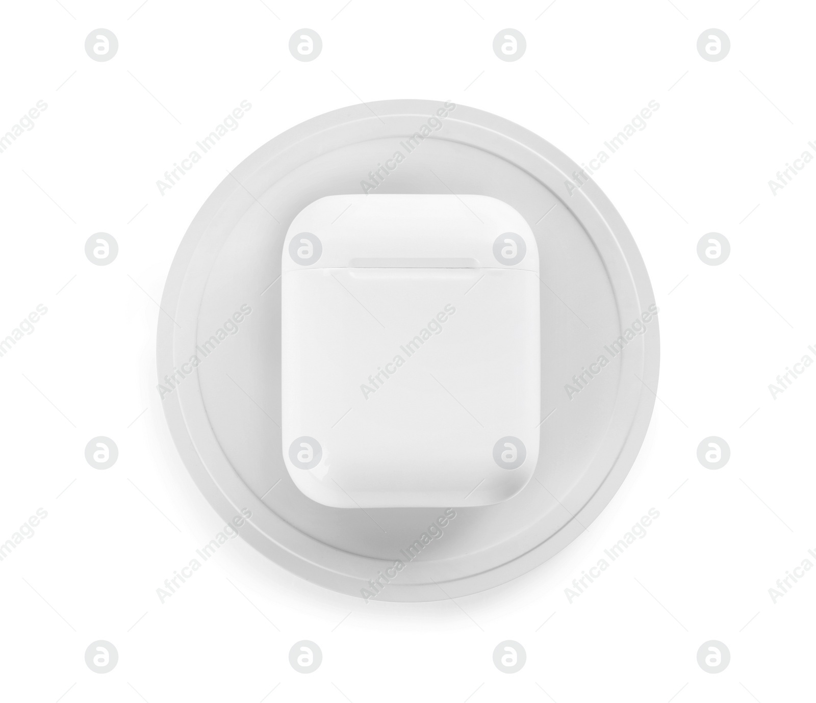 Photo of Earphones charging with wireless pad isolated on white, top view