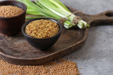 Serving board with delicious whole grain mustard, seeds and fresh green onion on grey table, closeup
