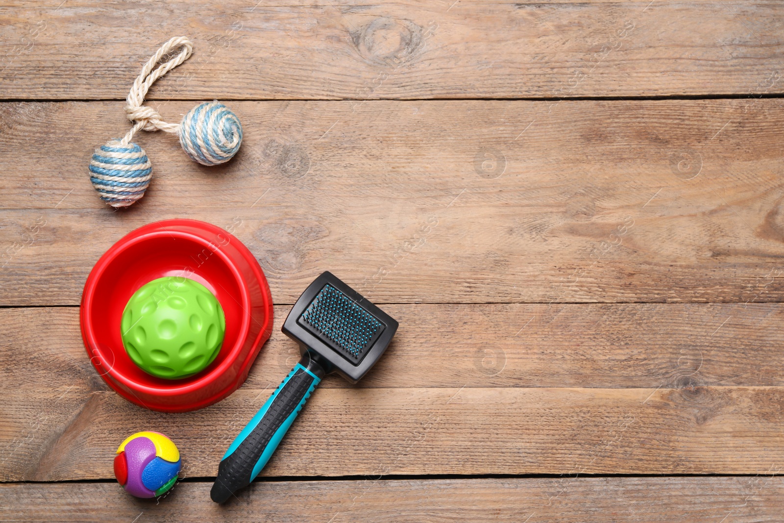 Photo of Pet toys, bowl and brush on wooden table, flat lay. Space for text