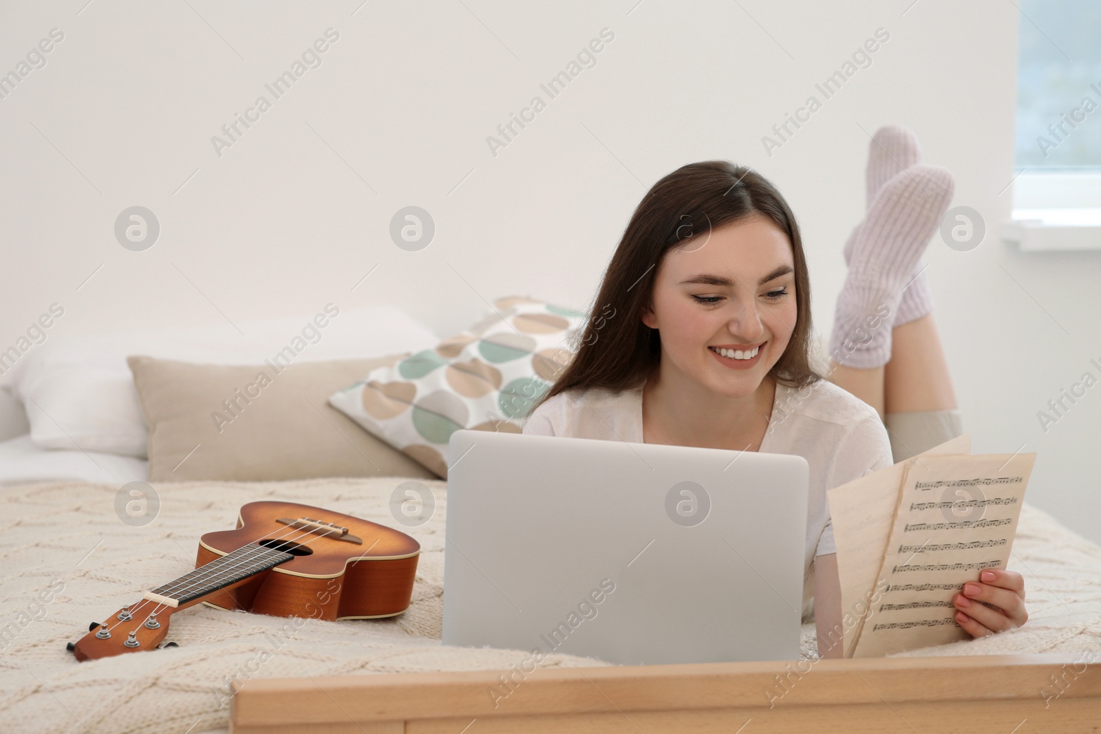 Photo of Woman learning to play ukulele with online music course at home. Space for text