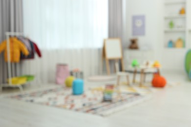 Blurred view of child`s playroom with different toys and furniture. Stylish kindergarten interior
