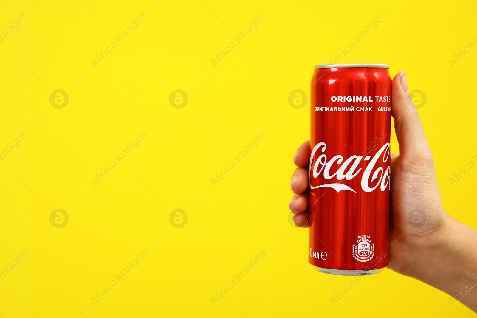 Photo of MYKOLAIV, UKRAINE - NOVEMBER 14, 2018: Woman holding Coca-Cola can on color background. Space for text