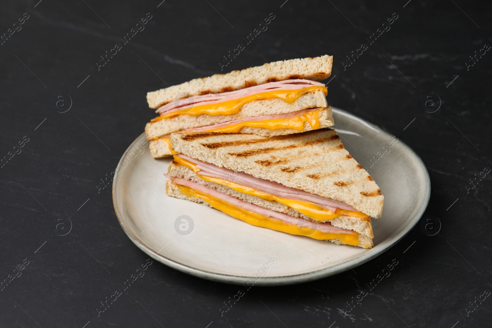 Delicious grilled sandwiches with ham and cheese on black table Photo of Delicious grilled sandwiches with ham and cheese on black table