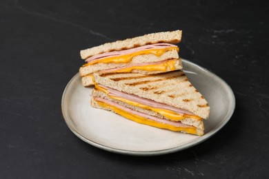 Photo of Delicious grilled sandwiches with ham and cheese on black table