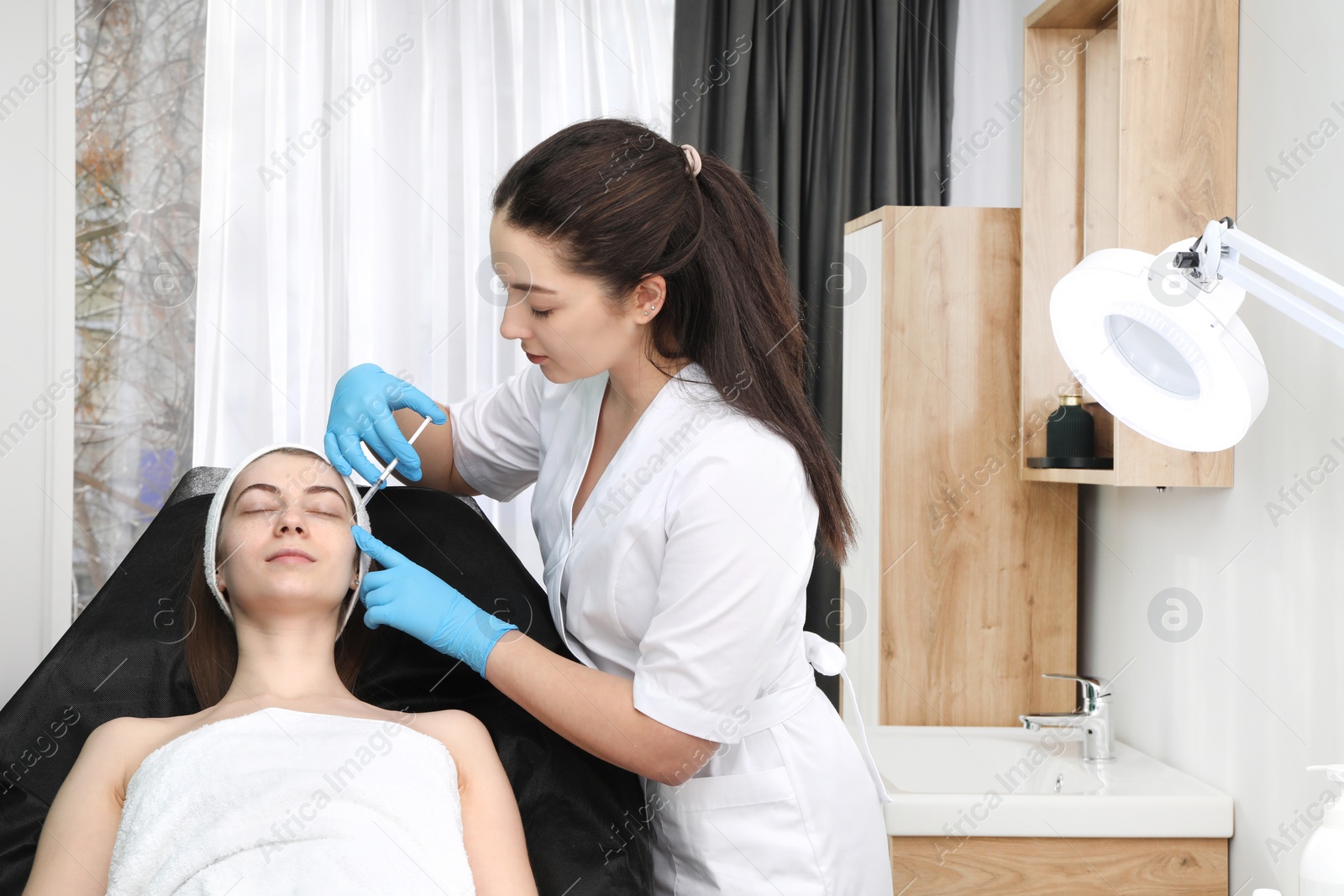 Photo of Cosmetologist giving facial injection to patient in clinic. Cosmetic surgery