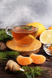 Glass cup of delicious immunity boosting tea and ingredients on wooden table