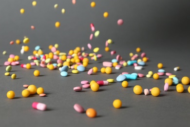 Photo of Different pills falling on table against gray background