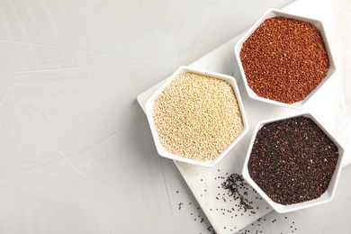 Bowls with different types of quinoa and space for text on light background, top view