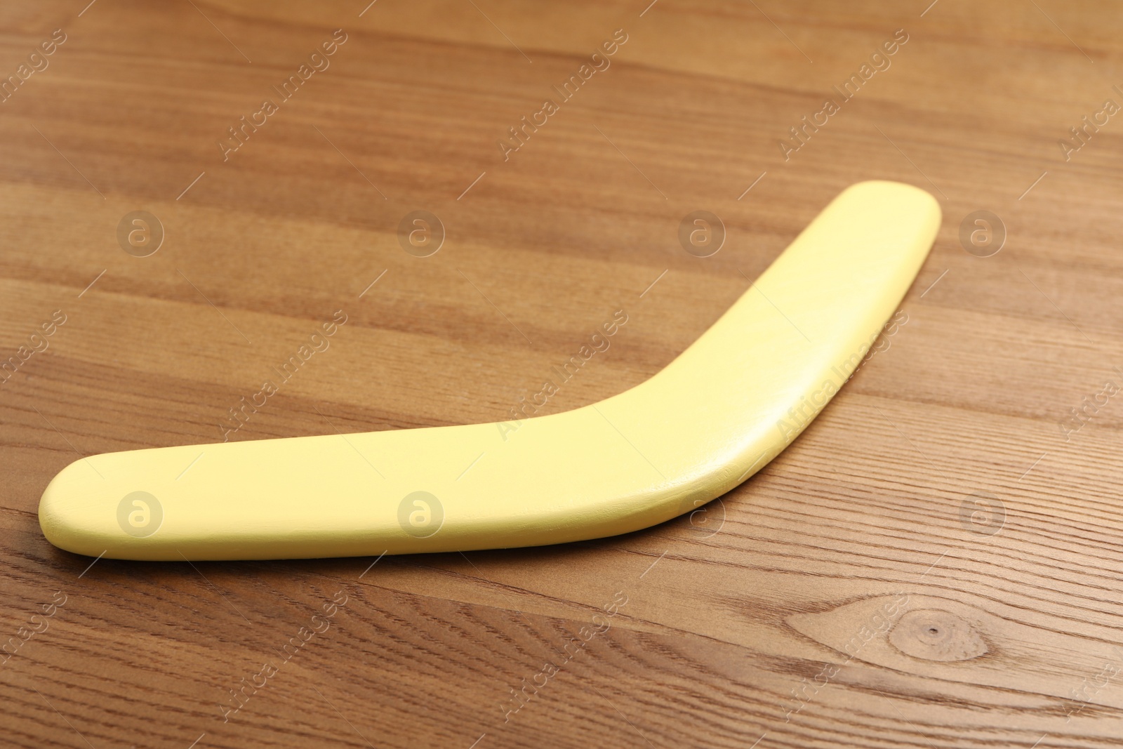 Photo of Yellow boomerang on wooden background. Outdoors activity