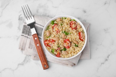 Delicious quinoa salad with tomatoes, beans and parsley on white marble table, top view