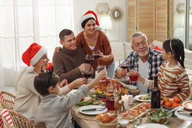 Photo of Happy family clinking glasses of drinks at festive dinner indoors. Christmas celebration