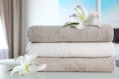 Stack of fresh towels with flowers on table indoors