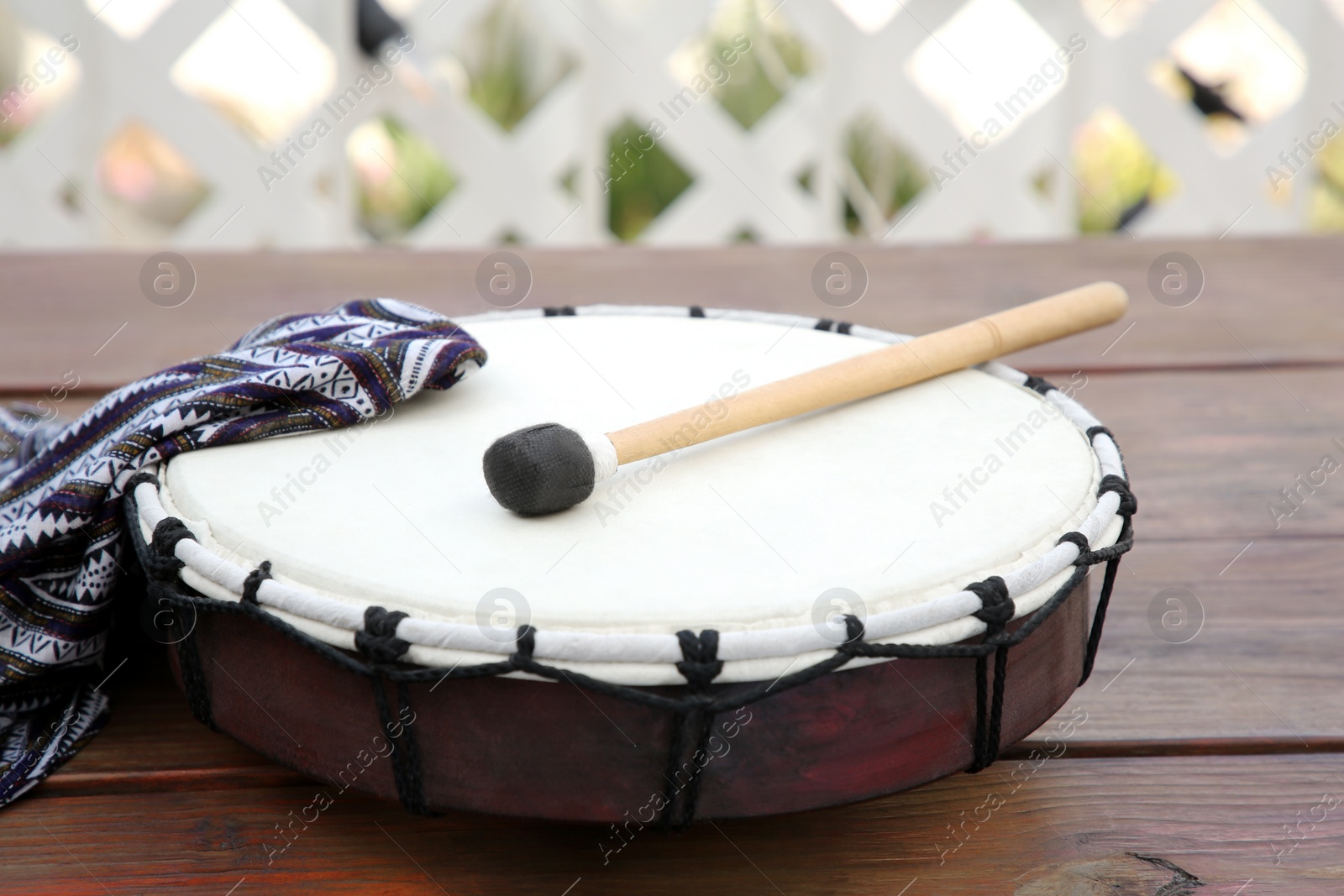 Photo of Modern drum with drumstick on wooden table