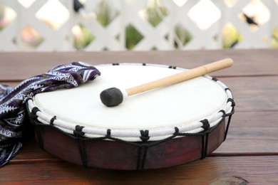 Photo of Modern drum with drumstick on wooden table