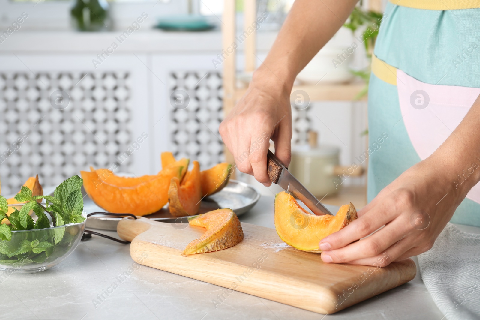 Photo of Woman slicing fresh ripe melon on light table