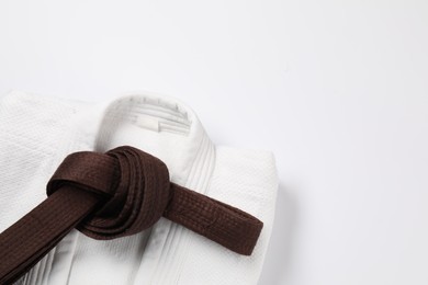 Brown karate belt and kimono on white background, top view. Space for text