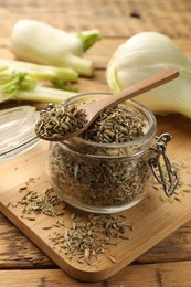Jar and spoon with fennel seeds on wooden table, closeup