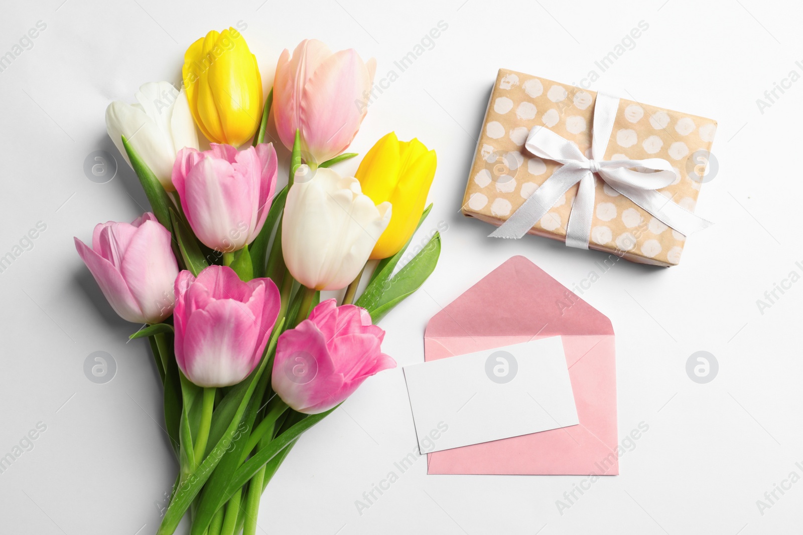 Photo of Flat lay composition of tulips and blank card on white background, space for text. International Women's Day