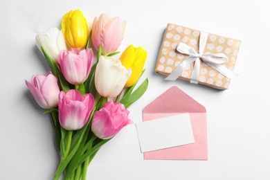 Photo of Flat lay composition of tulips and blank card on white background, space for text. International Women's Day