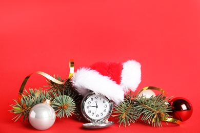 Photo of Pocket watch and festive decor on red background, space for text. New Year countdown