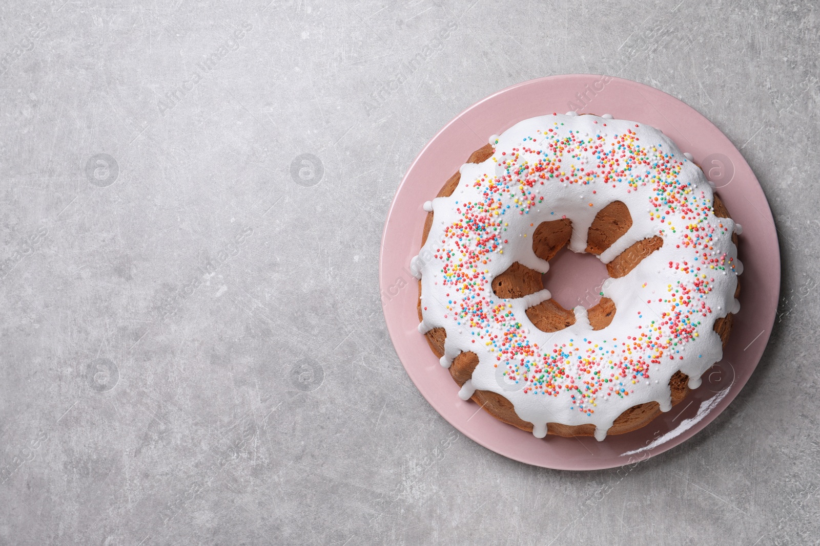 Photo of Glazed Easter cake with sprinkles on grey table, top view. Space for text